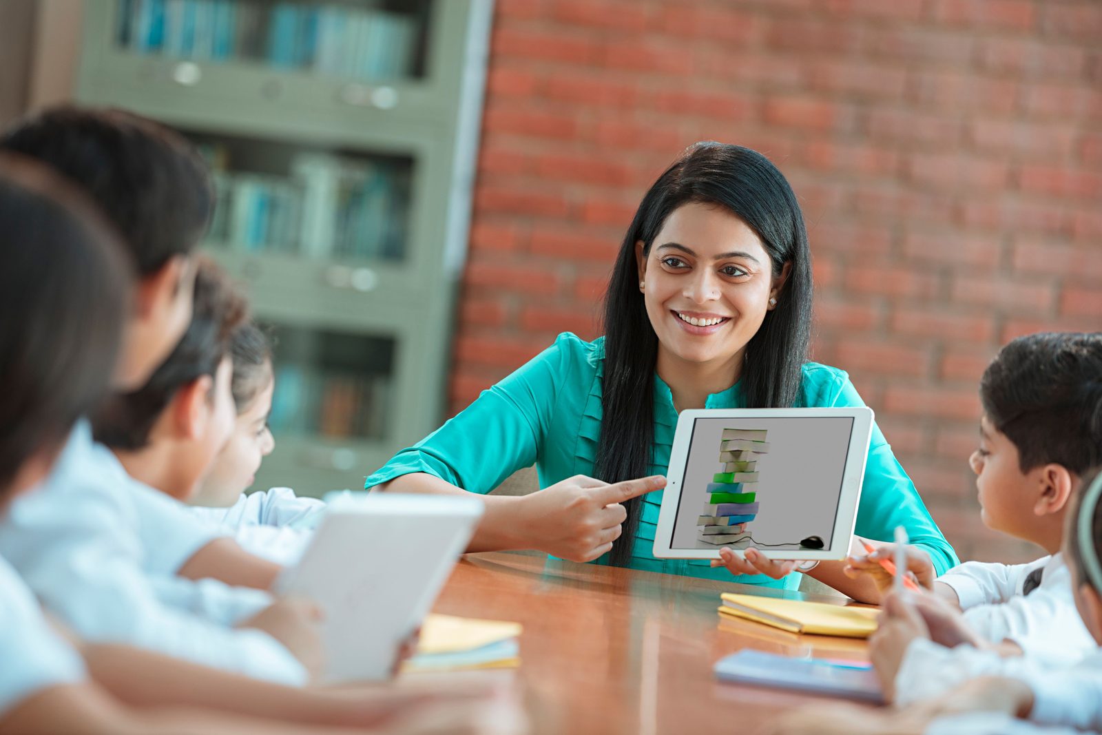 A teacher showing a tablet to a group of students in class